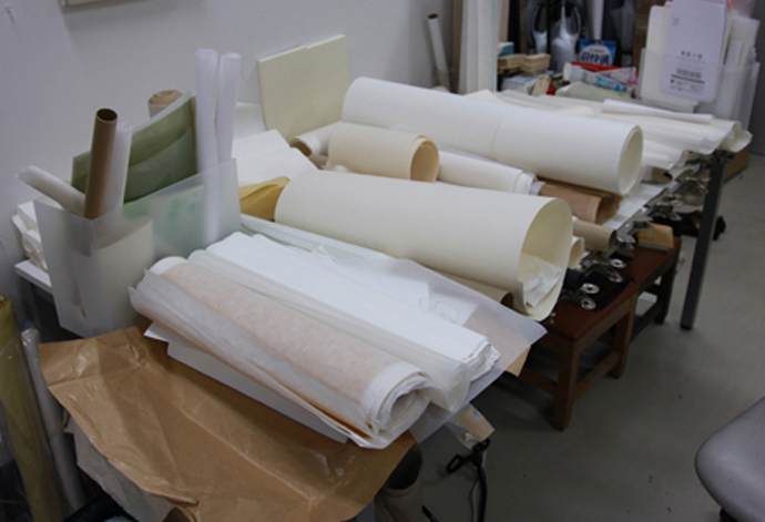 アトリエの一角に置かれた和紙の山。日本画の制作はある意味で、「和紙など製作者との”合作”」と川崎は語る。様々に個性ある和紙を使いながら、素材に合った表現を探すのだという。