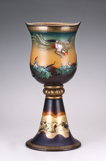 平和の世にのみ姿を現わすといわれる神鳥「鳳凰」。<br />
色鮮やかな翼を翻し飛ぶ姿は、縁起物として古来多くの美術品に描かれた。世の平和を祈り、ガラス素材の神秘に想いを重ね合わせ、技能を集約し挑戦した作品。