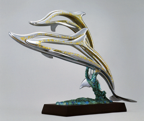 大海原を群遊するイルカ達を船上から感動して観ながら創作していた。しかし昨年、バハマの海に潜り、海中でのイルカ達の動きが驚きの様相でありました。母と子の姿に出合い、母が子を思う心はすべて万物共通のものであることを知りました。その数々の姿の中の１ページを形体として表現しました。